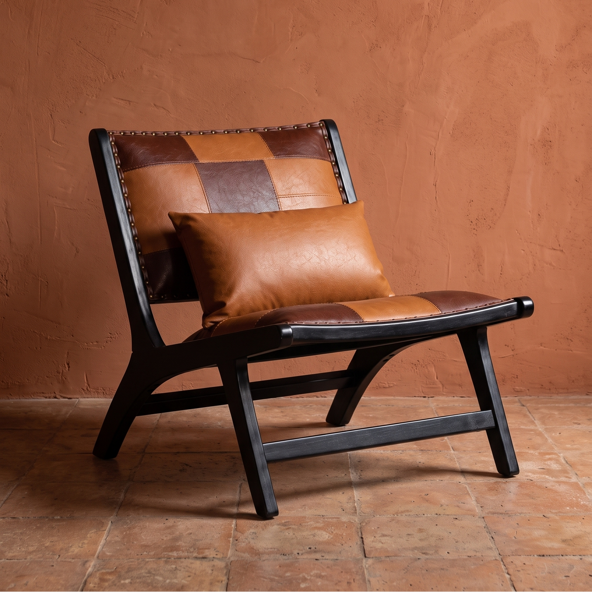 Patchwork leather-look lounge chair with black wood frame and lumbar pillow against a terracotta wall