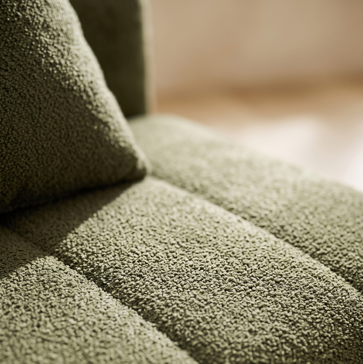 Close-up of olive green boucle channel tufting on a modular sofa seat cushion and throw pillow