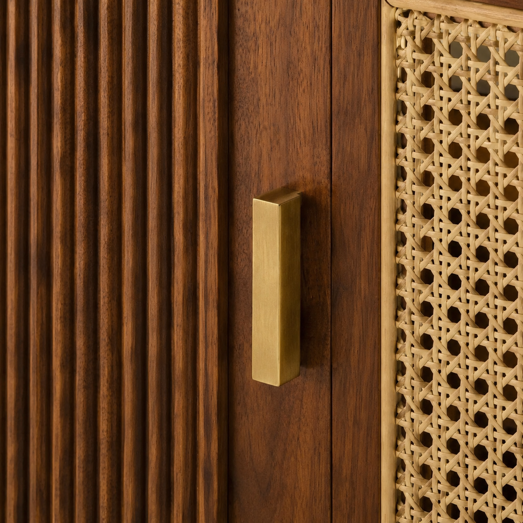 Brushed brass pull between fluted walnut door and natural rattan cane weave close-up