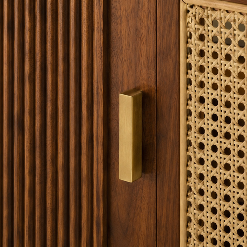 Brushed brass pull between fluted walnut door and natural rattan cane weave close-up